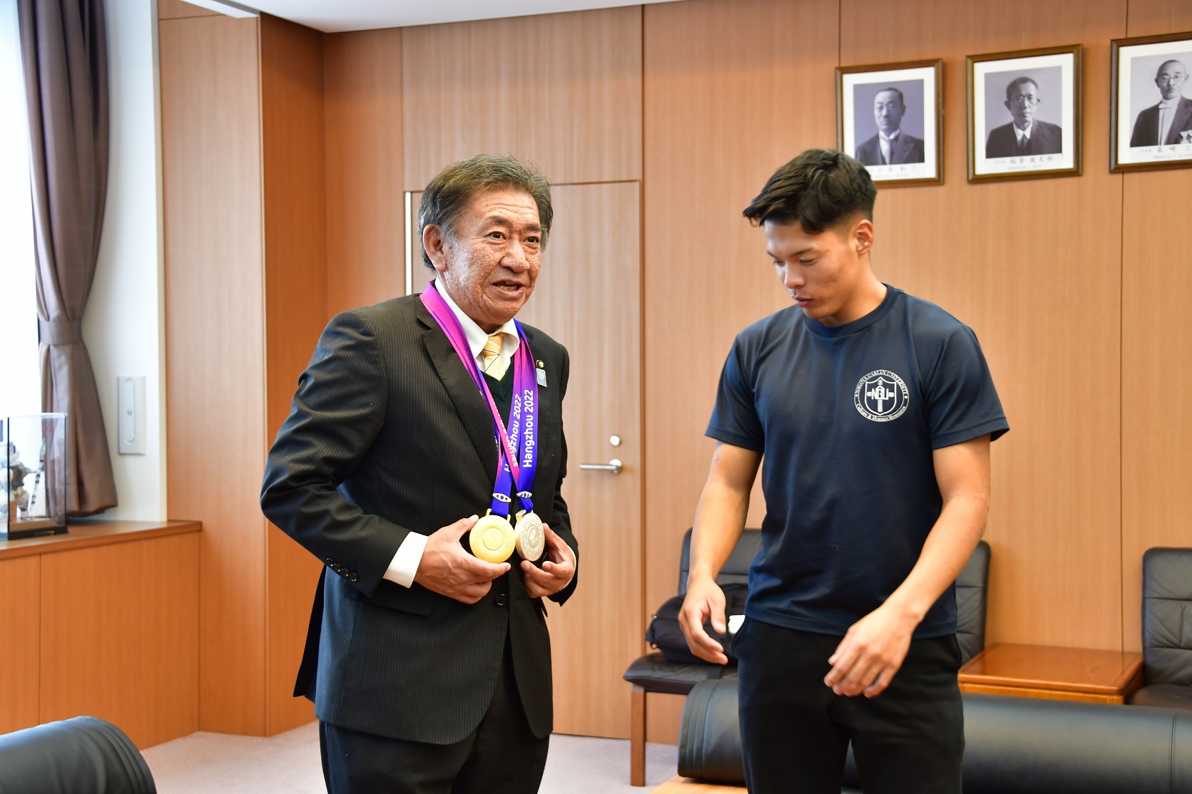 大島健吾選手から金メダルをかけられる市長