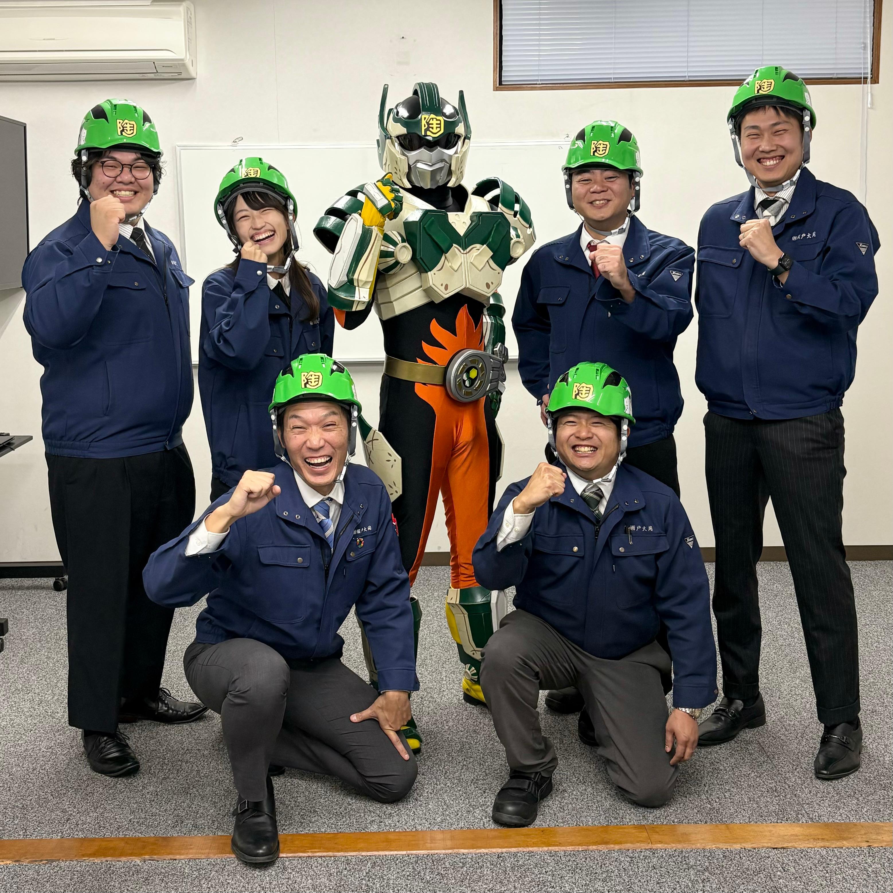 ご当地ヒーロー「陶神オリバー」とオリバーデザインのヘルメットを着用した株式会社瀬戸大同の社員の皆さんの画像